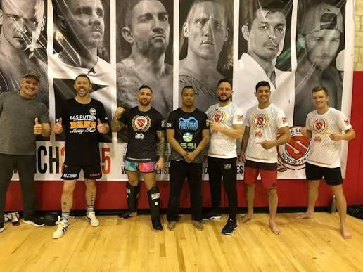 Jonathan Paul Ruiz with a seminar group beneath a wall of martial artist portraits