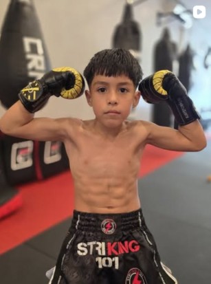 Young Striking 101 student posing with boxing gloves